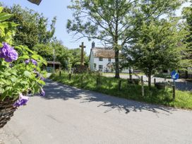 A view of a house with a cross and trees at Happiness Cottage in Piddlehinton