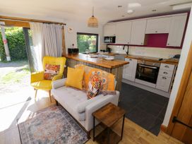 A kitchen and sitting area with a gray sofa and yellow chair next to a wooden counter at The Pheasant's Nest in Welland near Upton Upon Severn