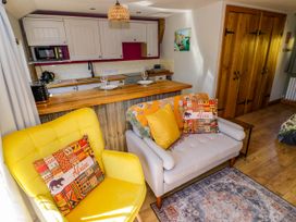 A small living room with yellow and grey chairs with cushions near a wooden kitchen counter at The Pheasant's Nest in Welland near Upton Upon Severn