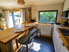 A kitchen with a wooden countertop and two plates with glasses and cutlery two gray bar stools a window showing greenery a radiator and a microwave at The Pheasant's Nest in Welland near Upton Upon Severn
