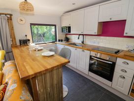 A kitchen with white cabinets wooden countertops a stove a sink and a breakfast bar with two plates and wine glasses at The Pheasant's Nest in Welland near Upton Upon Severn
