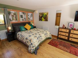 A bedroom with a bed decorated with patterned blankets and cushions beside bedside tables with lamps a dresser with drawers and a mirror on the wall at The Pheasant's Nest in Welland near Upton Upon Severn
