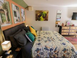 A bedroom with a bed covered in patterned bedding next to a nightstand with a lamp and a dresser with a mirror at The Pheasant's Nest in Welland near Upton Upon Severn