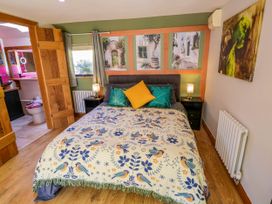 A bedroom with a bed covered with a patterned blanket and pillows with lamps on bedside tables at The Pheasant's Nest in Welland near Upton Upon Severn