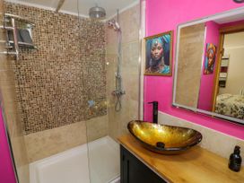 A bathroom with a shower area with tiled walls a wooden countertop with a vessel sink mirror and pink walls at The Pheasant's Nest in Welland near Upton Upon Severn