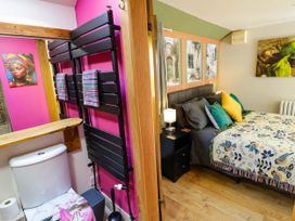 A bedroom with bed and bedside table next to a bathroom with toilet and towel rack at The Pheasant's Nest in Welland near Upton Upon Severn