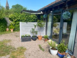 A garden patio with potted plants hanging baskets and a retractable awning at The Pheasant's Nest in Welland near Upton Upon Severn