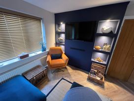 A living room with a television and shelves at Craster House in Seahouses