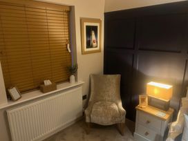 A bedroom with a chair and lamp at Craster House Seahouses