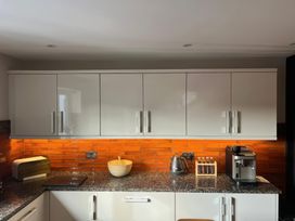A kitchen with cabinets, countertop, kettle, coffee machine, and bread box at Craster House in Seahouses