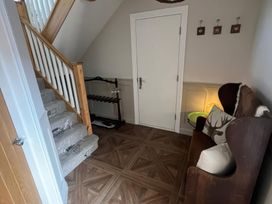 A hallway with stairs and a coat rack at Craster House Seahouses