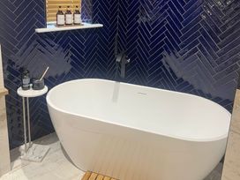 A bathroom with a bathtub and shelf at Craster House in Seahouses