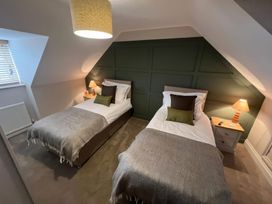 A bedroom with two beds and a bedside lamp at Craster House in Seahouses
