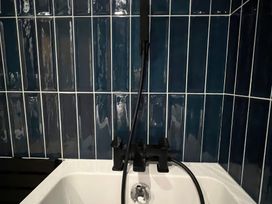 A bathtub with a faucet and tiled wall at Craster House in Seahouses