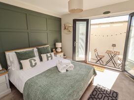 A bedroom with a bed and open doors leading to an outside area at Craster House in Seahouses