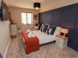 A bedroom with a bed, bedside table, and television at Craster House in Seahouses