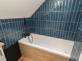 A bathroom with a bathtub and blue wall tiles at Craster House in Seahouses
