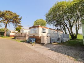 A mobile home with a blue bench and trees at No 29 Wyndham Hall in Cockermouth