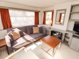 A living room with a purple sofa beige cushions coffee table lamp and mirror at No 29 Wyndham Hall in Cockermouth