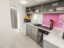 A kitchen with gray cabinets a gas stove a sink a microwave and an orange toaster at No 29 Wyndham Hall in Cockermouth