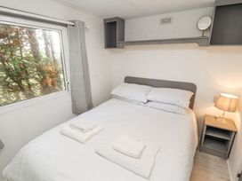 A bedroom with a double bed with white linens two towels on the bed a bedside table with a lamp and a window with grey curtains at No 29 Wyndham Hall in Cockermouth