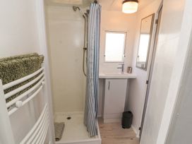 A small bathroom with a shower area and a sink under a window at No 29 Wyndham Hall in Cockermouth