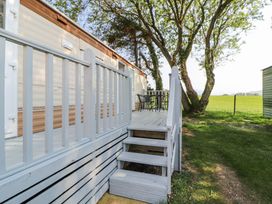 An outdoor deck with white railing and stairs next to a mobile home with a table and chairs on the deck at No 29 Wyndham Hall in Cockermouth