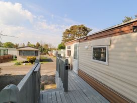 A row of mobile homes with a wooden deck and railing at No 29 Wyndham Hall in Cockermouth