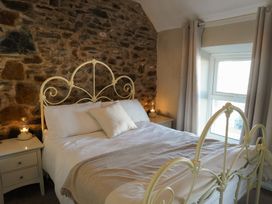A bedroom with a bed and stone wall at Rhianfa Newborough