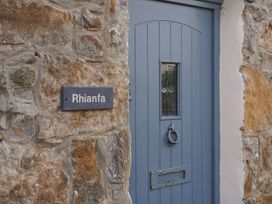 A front door with a stone wall and a sign at Rhianfa in Newborough