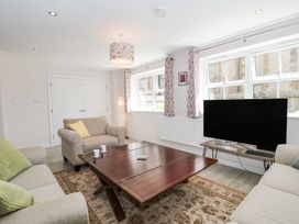 A living room with sofas a wooden coffee table a television and patterned curtains at The Coach House in Castle Cary