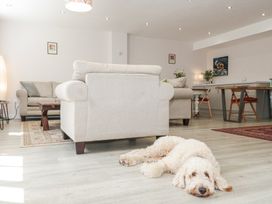 A living room with two beige sofas a wooden coffee table a wooden dining table with chairs and a dog lying on the floor at The Coach House in Castle Cary