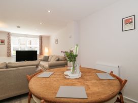 A dining table with placemats and flowers and a living room with sofas and a tv at The Coach House in Castle Cary