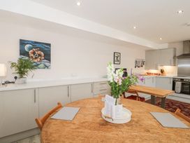 A kitchen with wooden dining table and chairs white cabinets and cooking utensils at The Coach House in Castle Cary