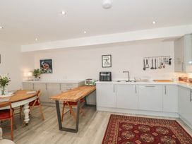 A kitchen with a wooden dining table and chairs a wooden countertop with appliances cabinets and a red patterned rug on the floor at The Coach House in Castle Cary