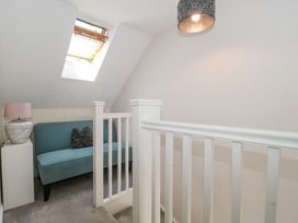 A small sitting area with a teal loveseat a side table with a lamp and a skylight window at The Coach House in Castle Cary