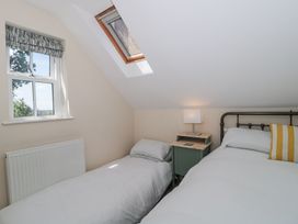A bedroom with two single beds a bedside table with a lamp a window and a skylight at The Coach House in Castle Cary
