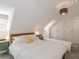 A bedroom with white bedding a wooden headboard green bedside tables under sloped ceilings at The Coach House in Castle Cary