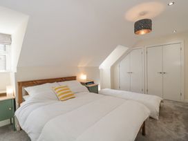 A bedroom with a double bed a single bed two green bedside tables and white closets at The Coach House in Castle Cary