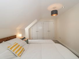 A bedroom with a wooden bed headboard white bedding yellow striped pillow bedside table lamp and white double closet doors at The Coach House in Castle Cary