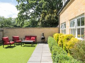 A backyard with red cushioned chairs and sofa around a coffee table and a brick wall at The Coach House in Castle Cary