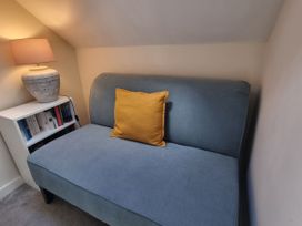 A sofa with a yellow cushion and a lamp in a living room at The Coach House in Castle Cary