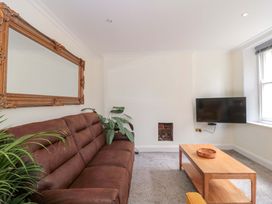 A living room with a sofa, a mirror, a television, and a coffee table at Flat 2 Battledown Grange, Cheltenham