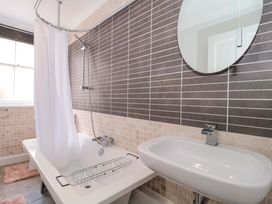 A bathroom with a bathtub, sink, and mirror at Flat 2 Battledown Grange in Cheltenham
