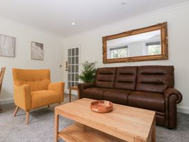 A living room with a sofa, armchair, coffee table, and mirror at Flat 2 Battledown Grange Cheltenham