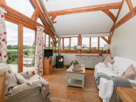 A living room with a fireplace and large windows at Little Acorn Cottage in Munsley near Ledbury
