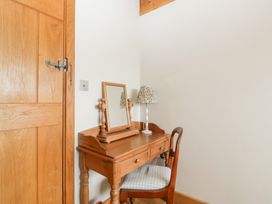 A dressing area with a table and lamp at Little Acorn Cottage in Munsley near Ledbury