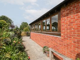 A garden view with a brick wall and pathway at Little Acorn Cottage in Munsley near Ledbury