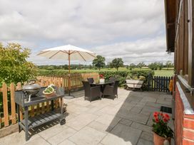 A patio with a table, chairs, barbecue grill and a parasol at Little Acorn Cottage in Munsley near Ledbury
