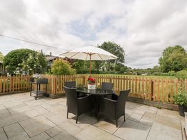 A garden with a table and chairs under an umbrella at Little Acorn Cottage in Munsley near Ledbury